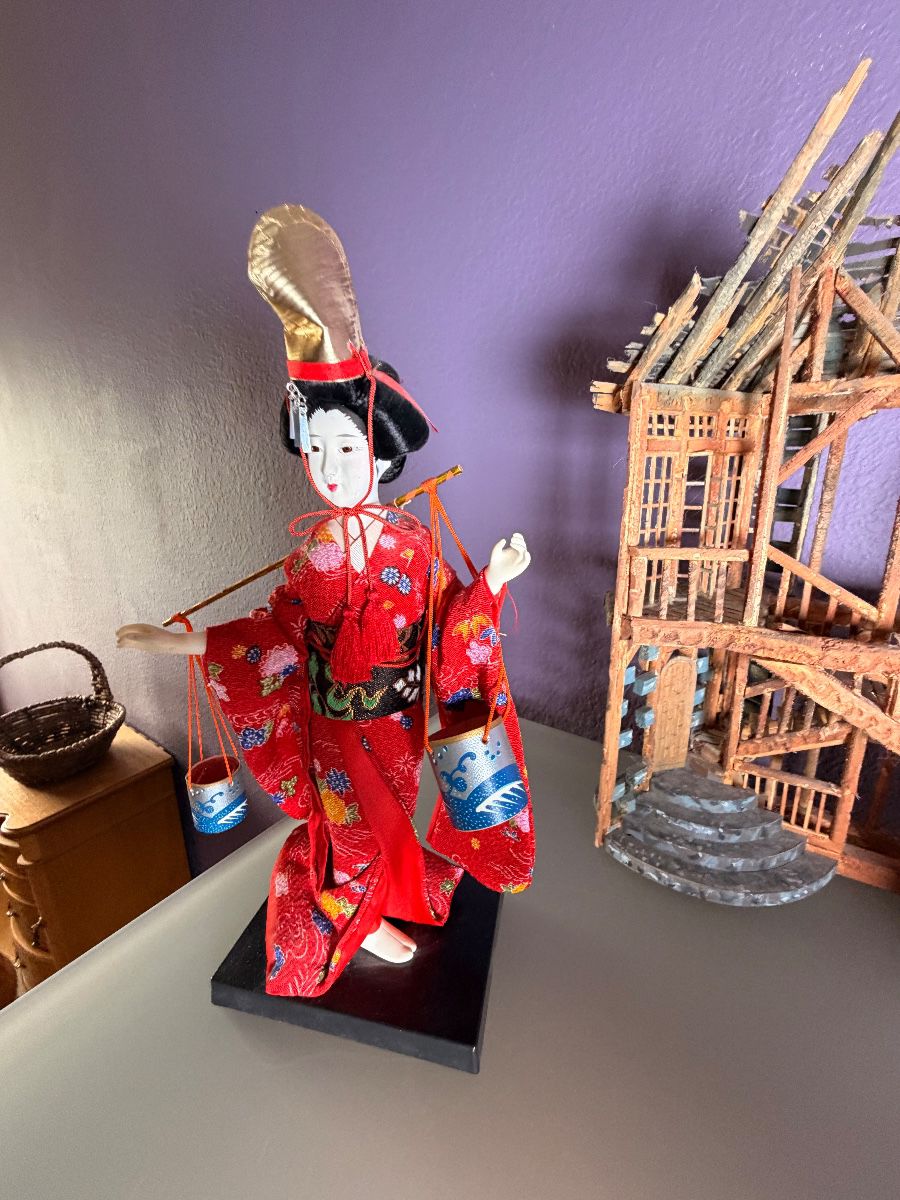 Asian dolls in traditional dress beside a carved wooden pagoda