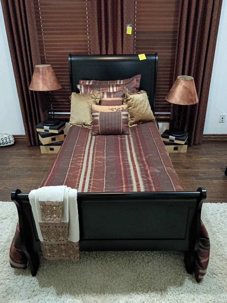 Black wood sleigh bed with striped bedding and table lamps