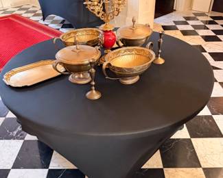 Brass serving bowls, tureens and candlesticks on a round table