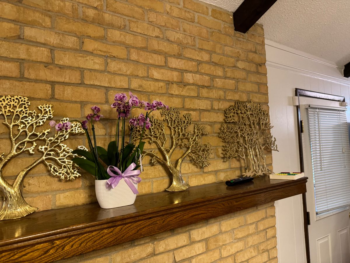 Brass tree sculptures on a brick mantel at a Bedford estate sale