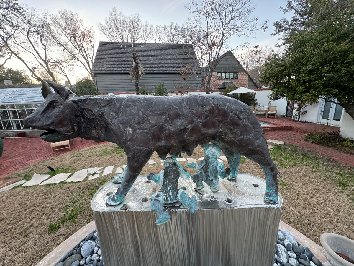 Bronze Capitoline wolf garden sculpture on a stone fountain base