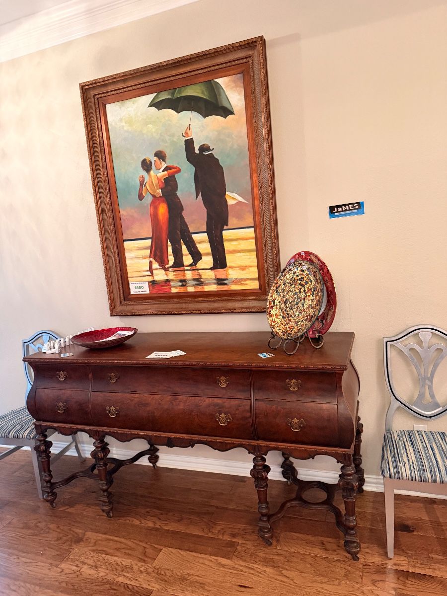 Carved wood sideboard below a framed dancing couple print