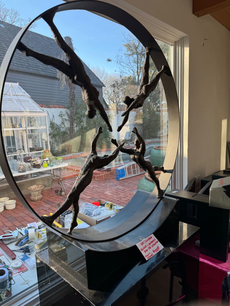 Circular bronze dancers sculpture by a window
