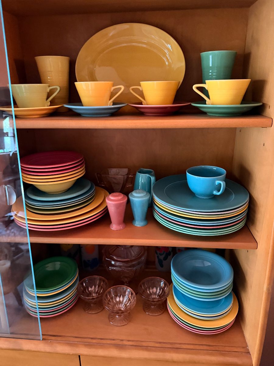 Colorful vintage solid color dinnerware stacked in a cabinet