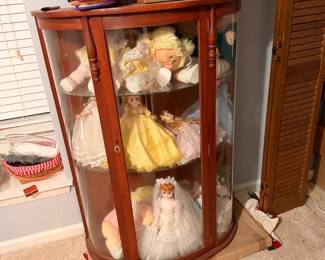 Curved glass curio cabinet filled with collectible dolls at an Arlington estate sale