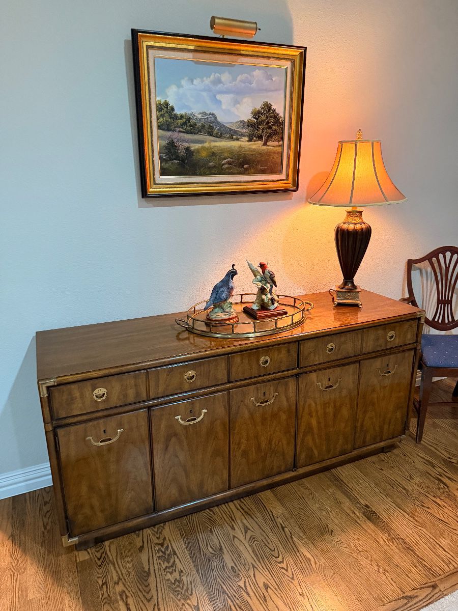Drexel wood credenza below a framed landscape painting