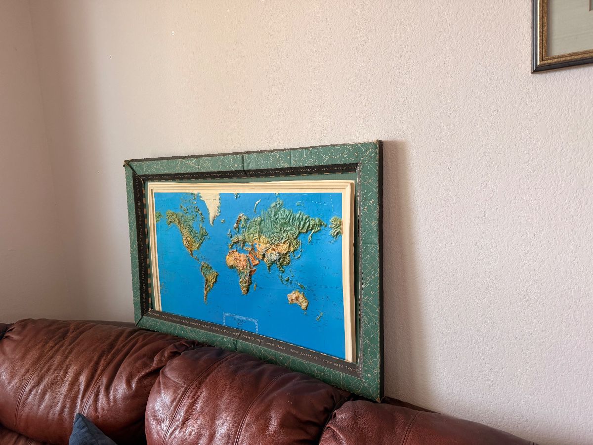 Framed raised-relief world map with a green frame