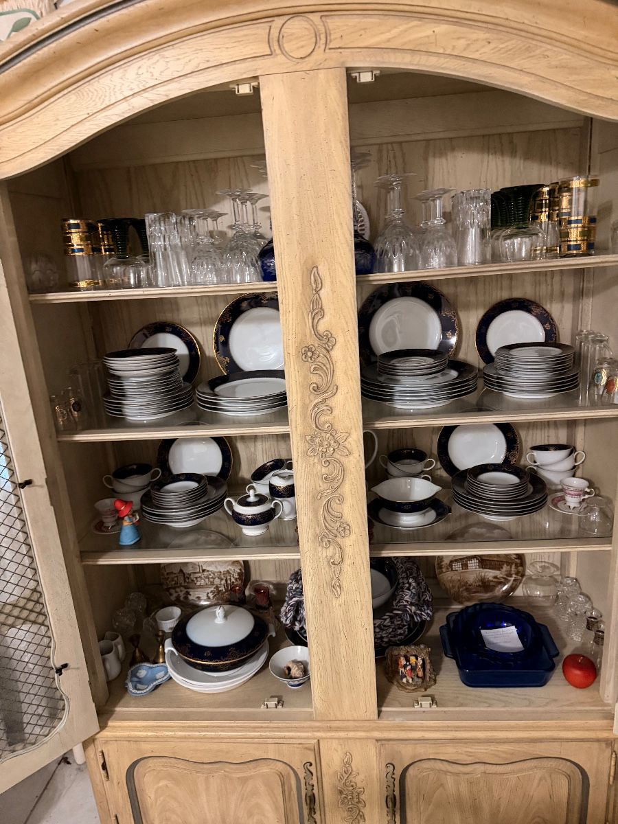 French provincial china cabinet filled with dinnerware and glassware