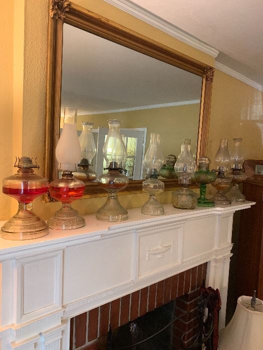 Gold framed mirror over a mantel of oil lamps