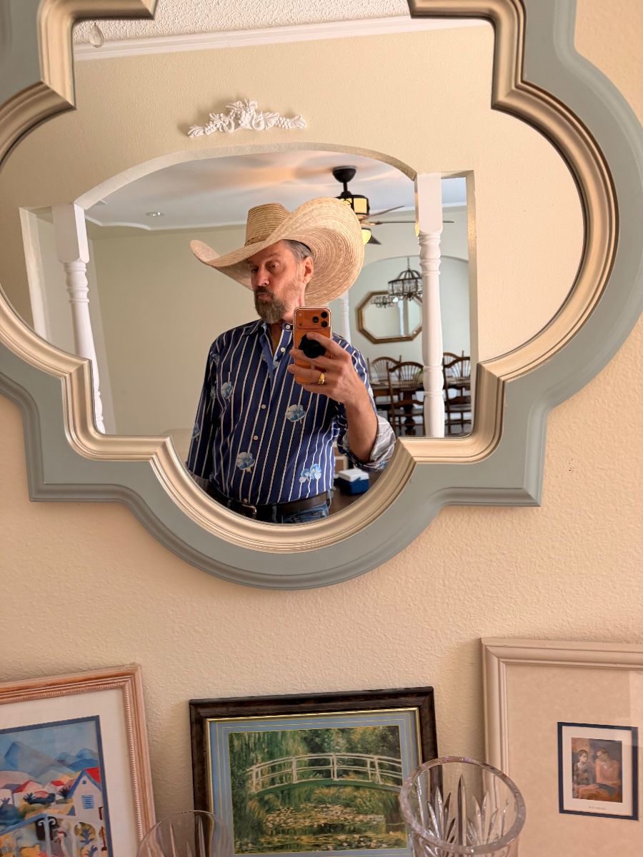 James Major of James Major Estate Sales in a straw cowboy hat, reflected in a scalloped mirror