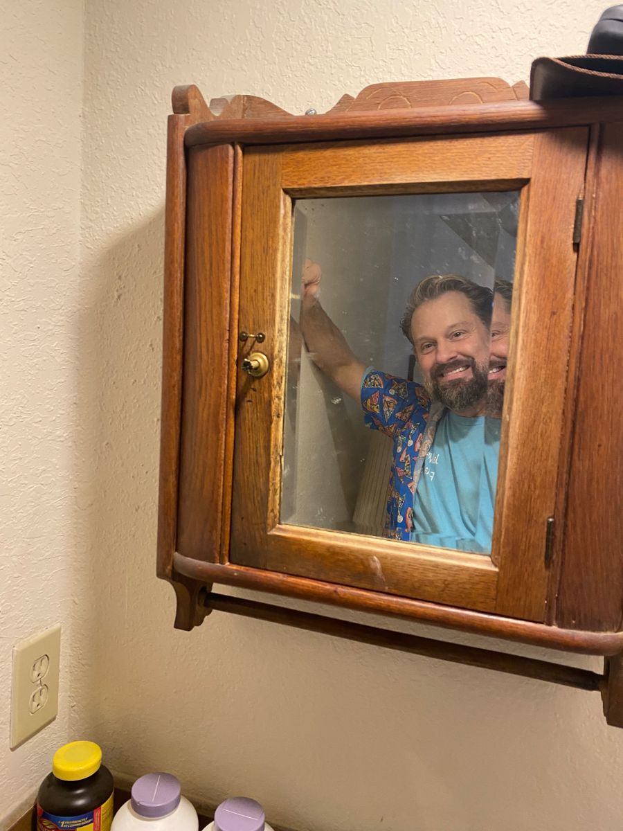 James Major of James Major Estate Sales peeking through an antique medicine cabinet