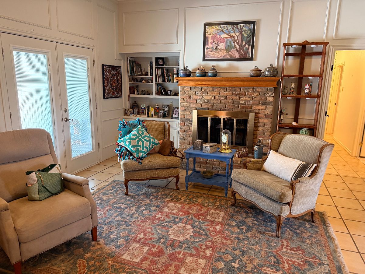 Living room with a brick fireplace, armchairs and a Persian style rug