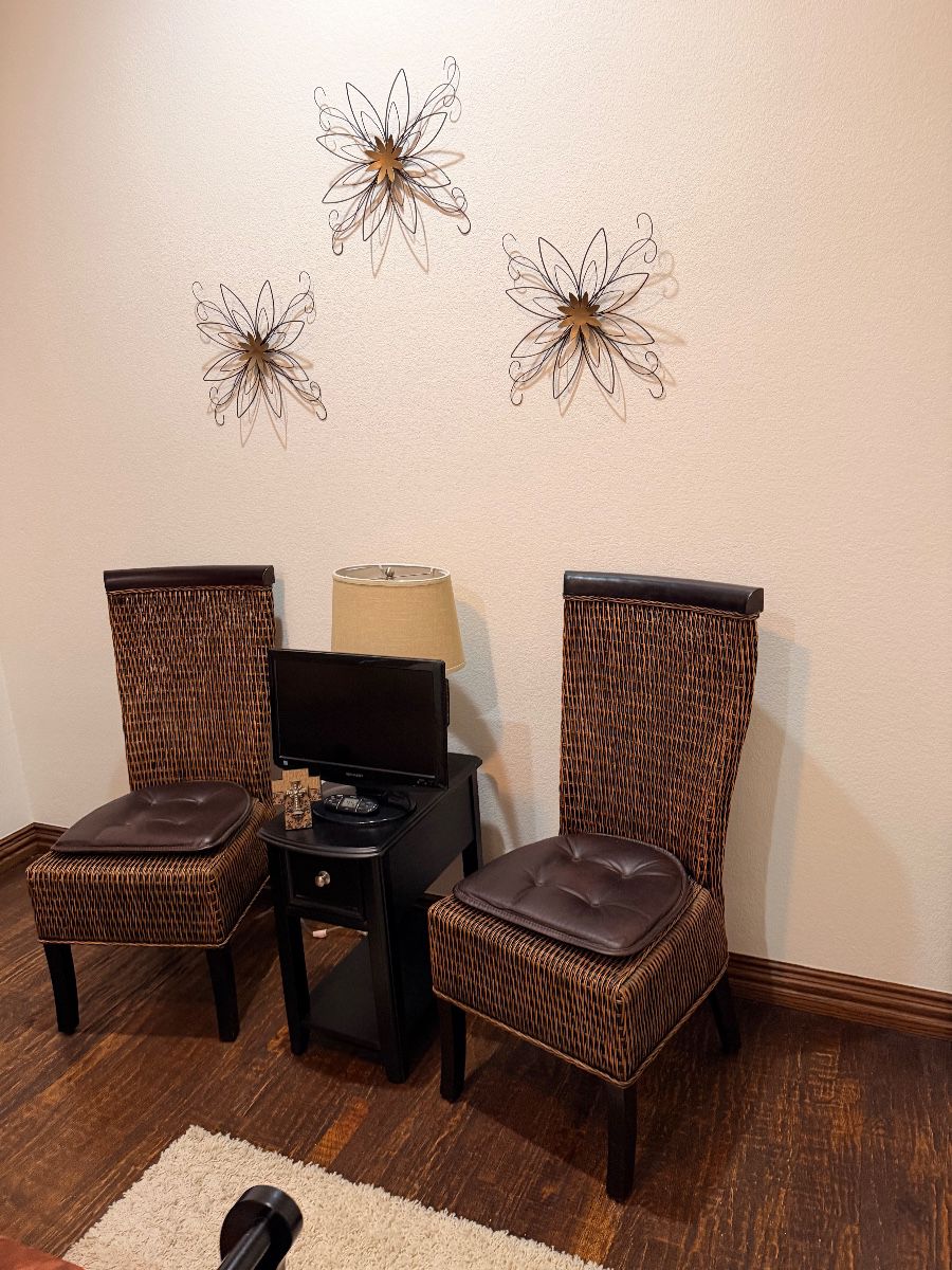 Pair of woven dining chairs below metal starburst wall decor