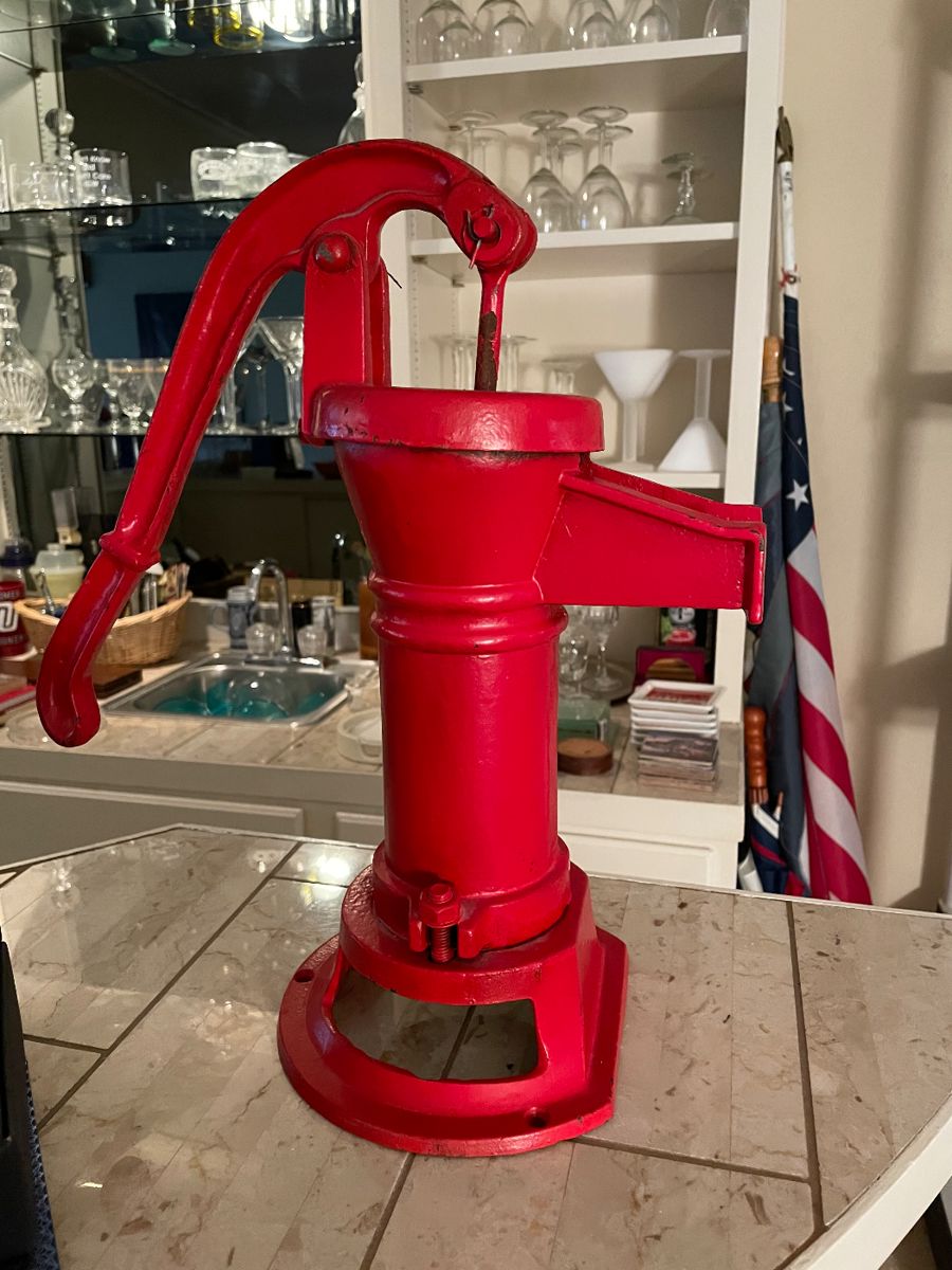 Red cast iron pitcher pump on a marble counter