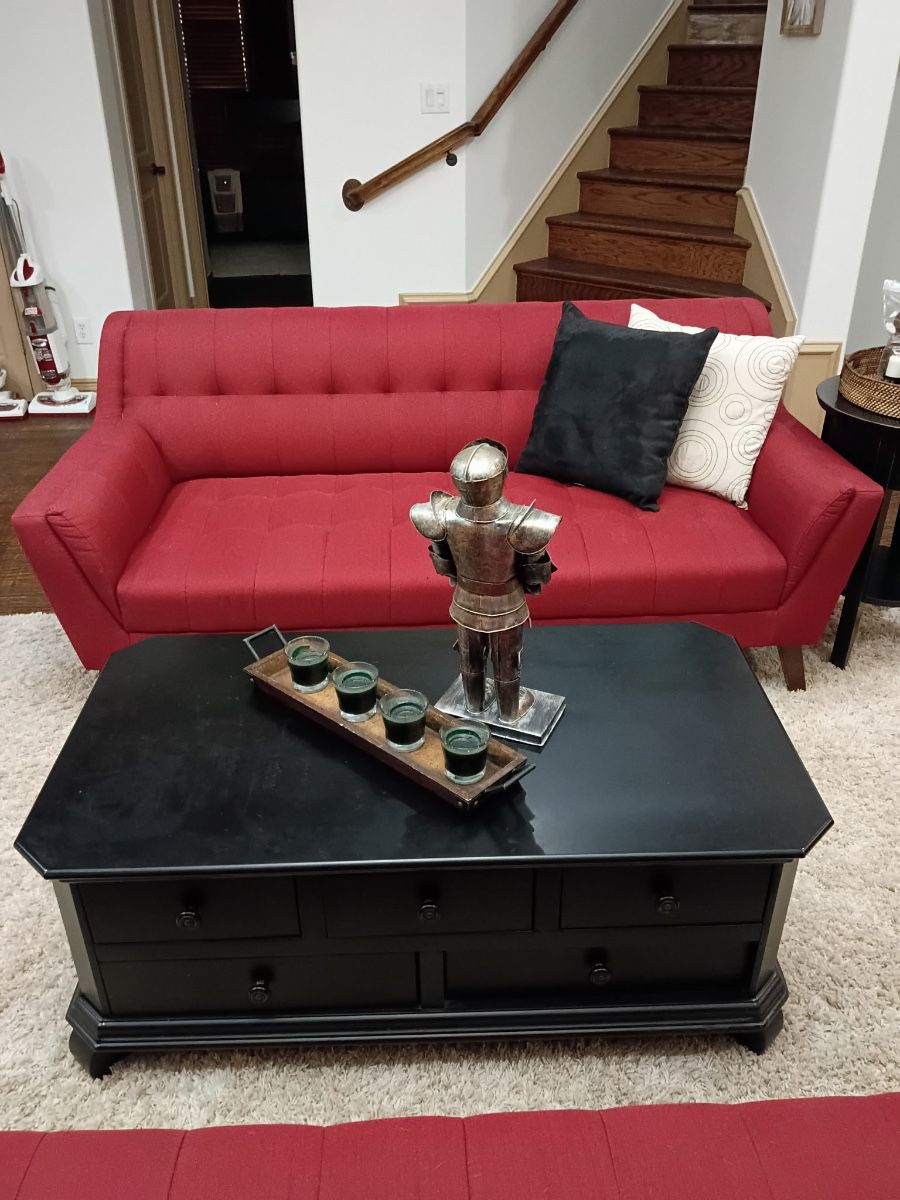 Red tufted sofa with throw pillows and black wood coffee table