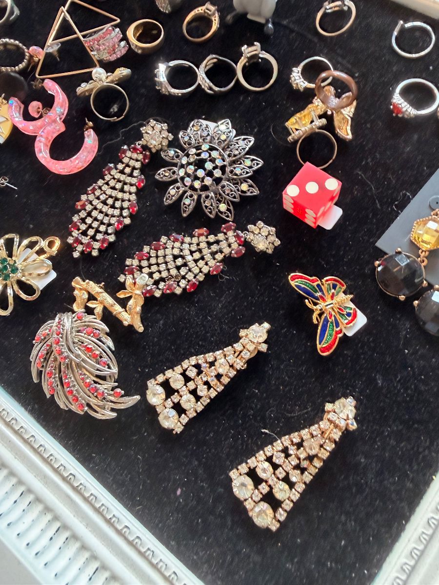 Rhinestone brooches, earrings and costume rings on a black jewelry tray