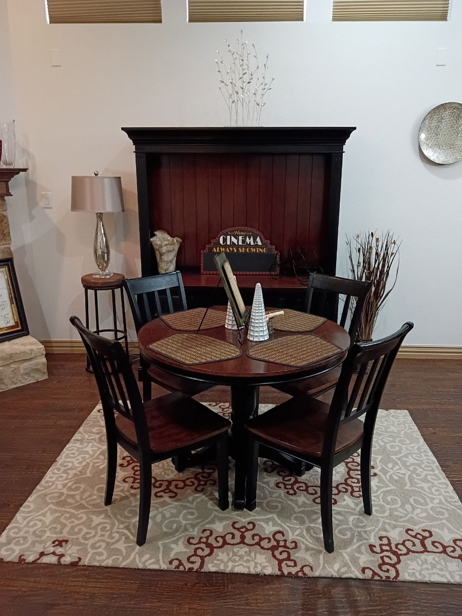 Round pub table and chairs in front of a black wood bar cabinet
