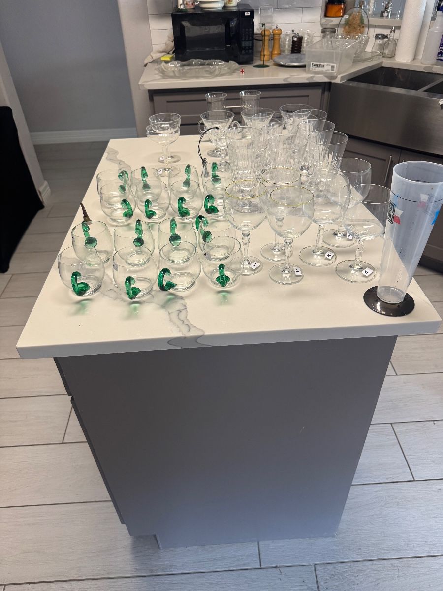 Rows of green-stem crystal wine glasses and stemware on a kitchen island