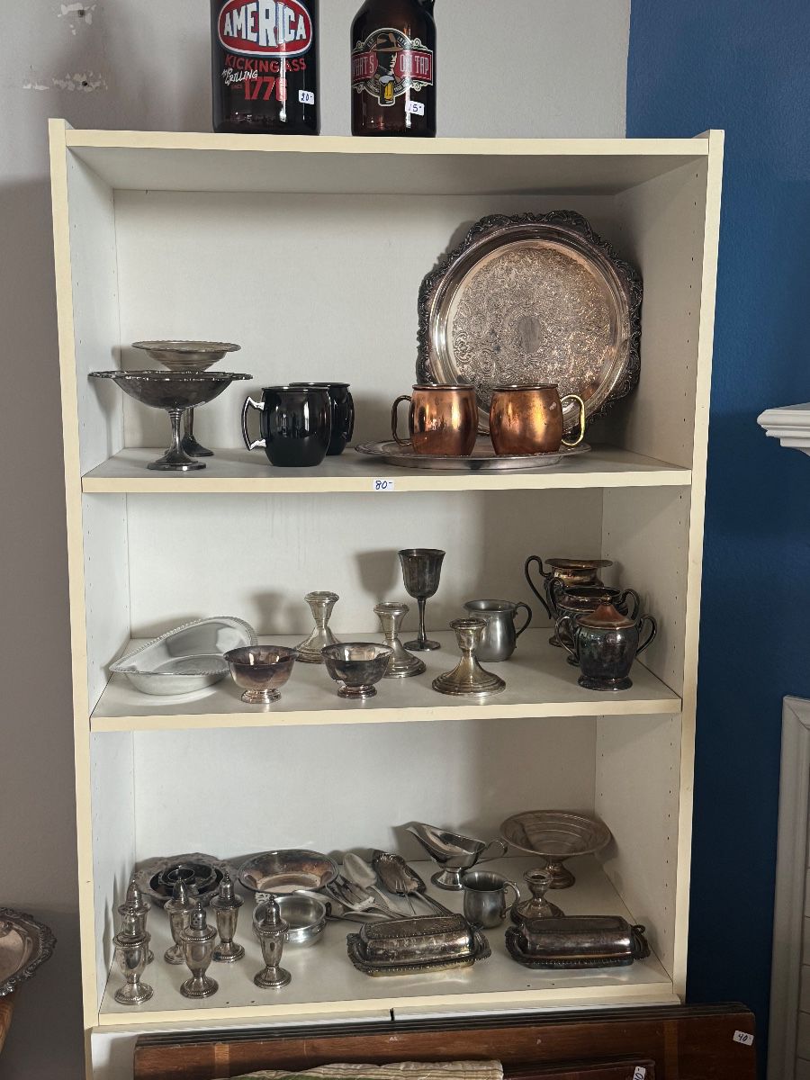 Shelves of silver-plated trays, goblets, creamers and copper mugs