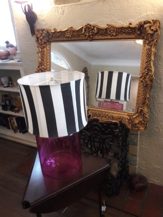 Striped lamp in front of an ornate gilt mirror