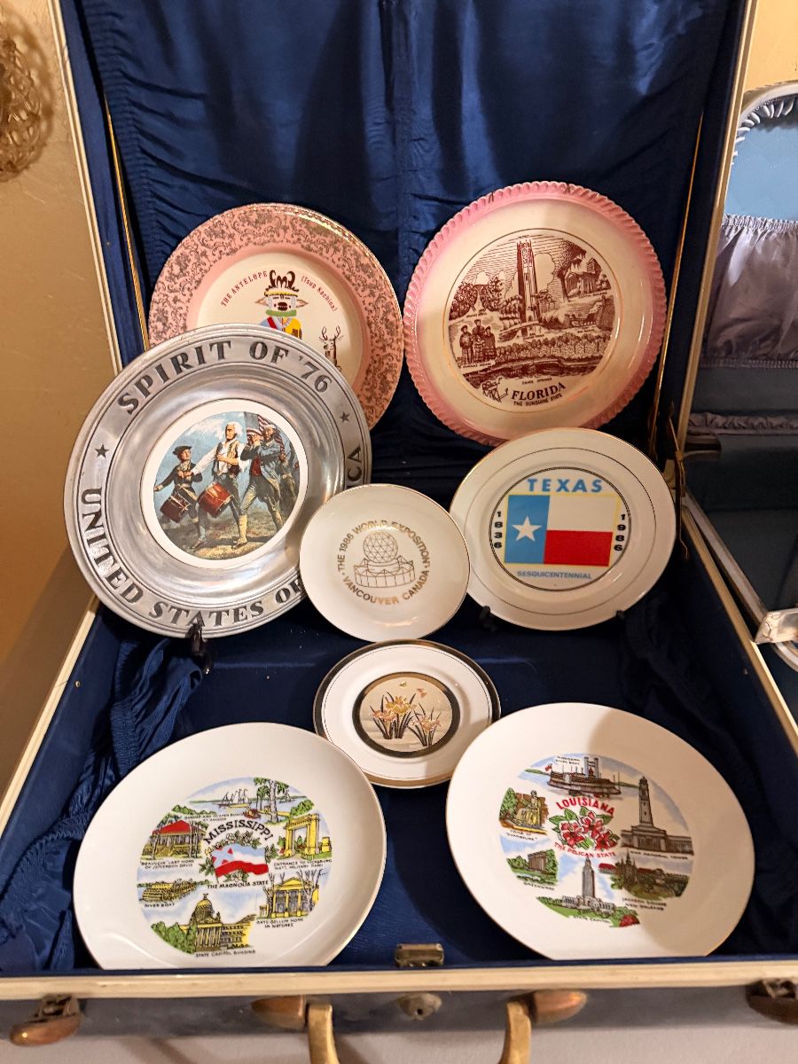 Travel souvenir plate collection in a vintage suitcase